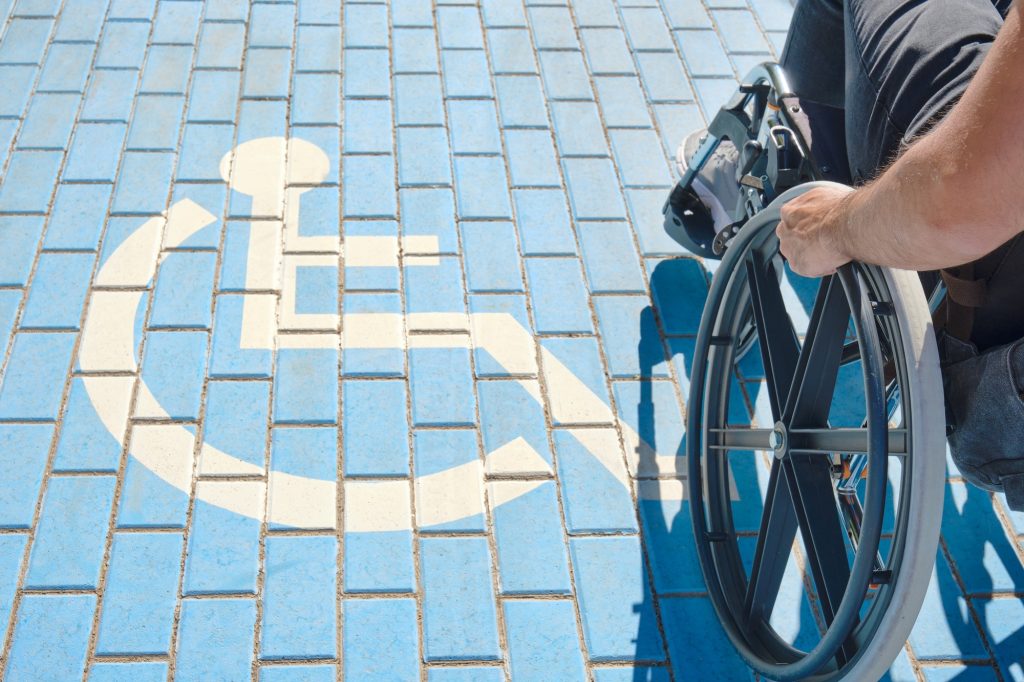 disabled person in a wheelchair walking past a disabled parking sign